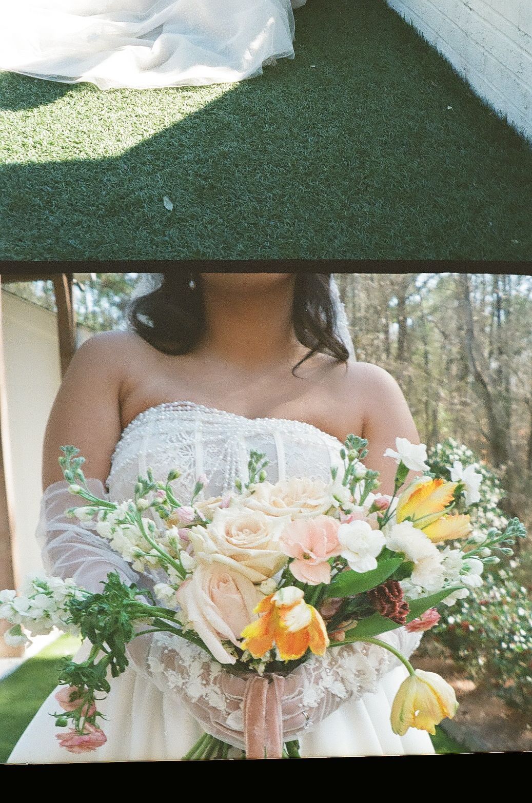 A romantic bridal bouquet featuring peach roses, yellow tulips and delicate white baby's breath against a lace wedding dress.