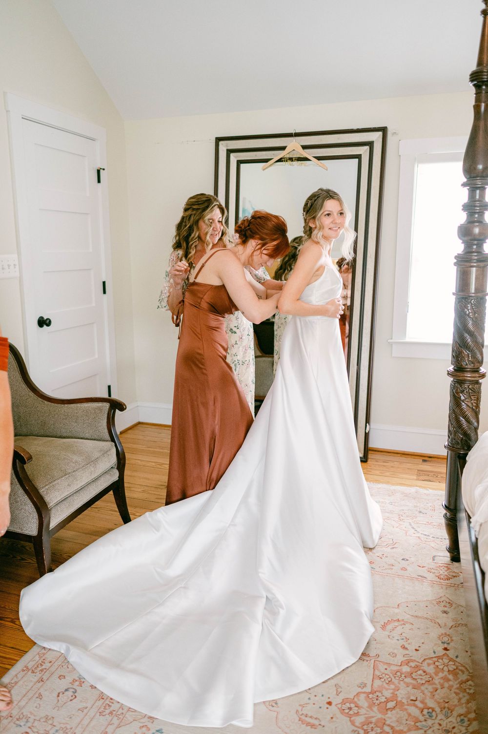 Wedding dress preparations in a bright white room with hardwood floors.