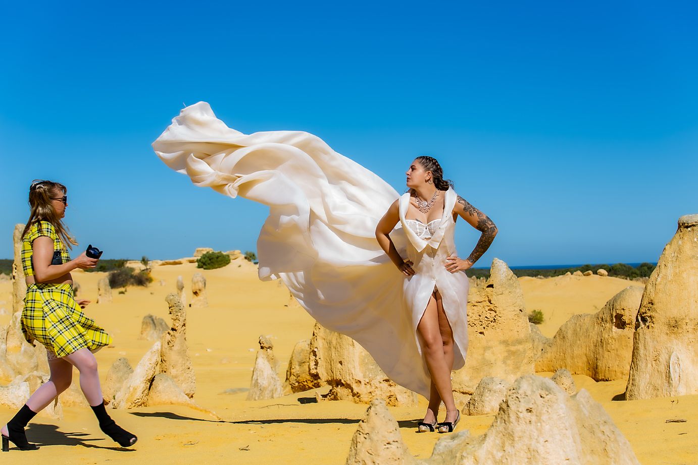 Wind-blown white fabric flows against bright blue sky and sandy desert pinnacle landscape in artistic sequence.