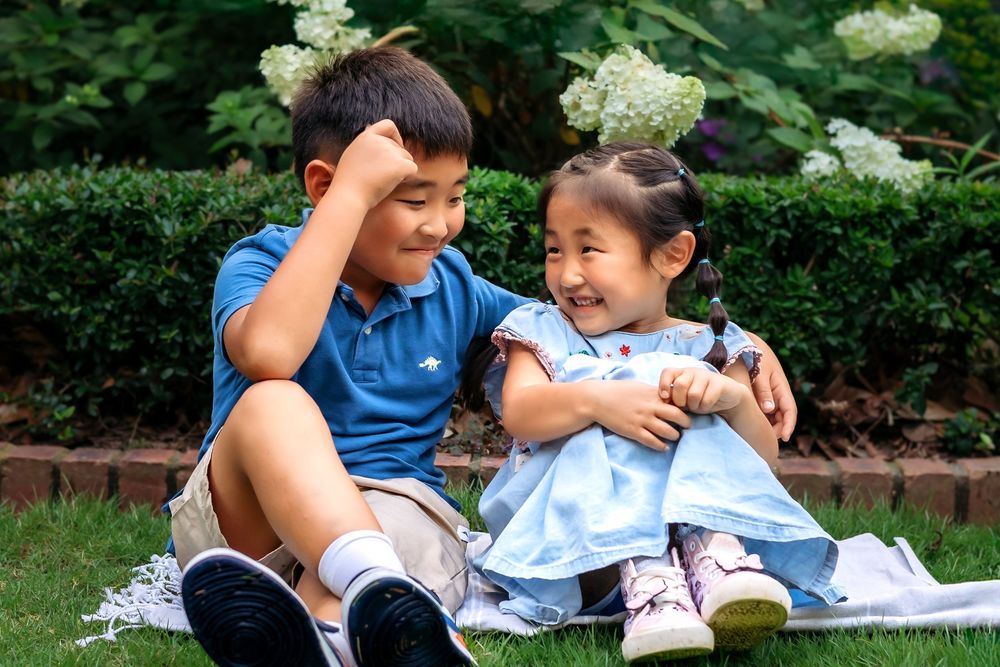 Siblings smiling together during lifestyle family session at UGA Founders Garden in Athens GA