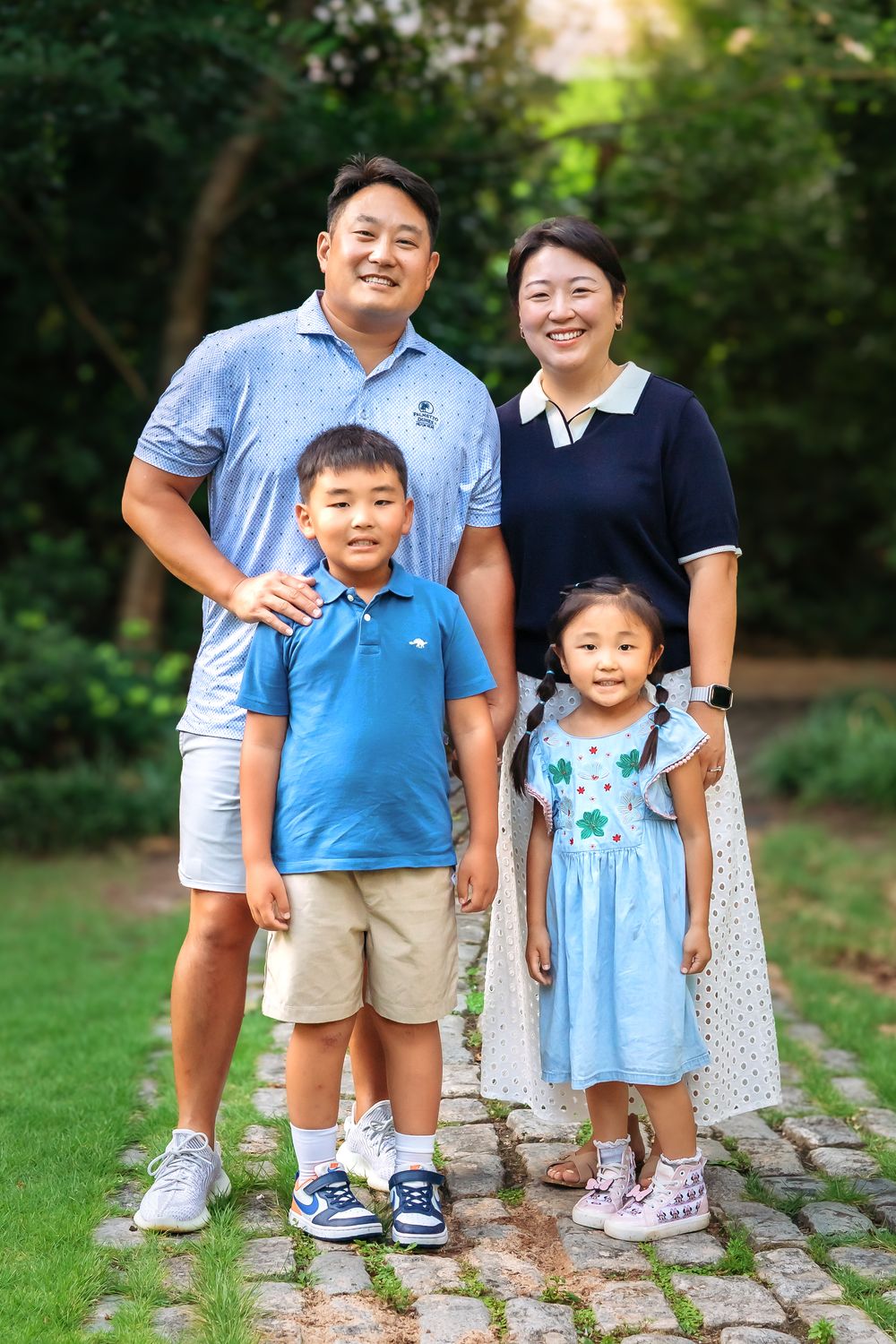 Sweet family moment captured at Founders Garden with blooming greenery and stone path during family session in Athens GA