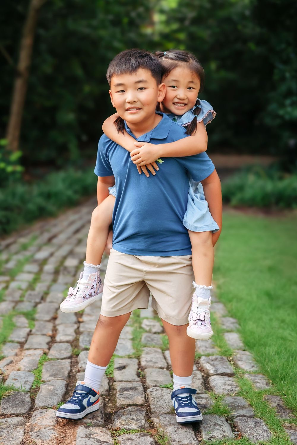 Big brother giving little sister a piggyback ride during family session at UGA Founders Garden in Athens GA