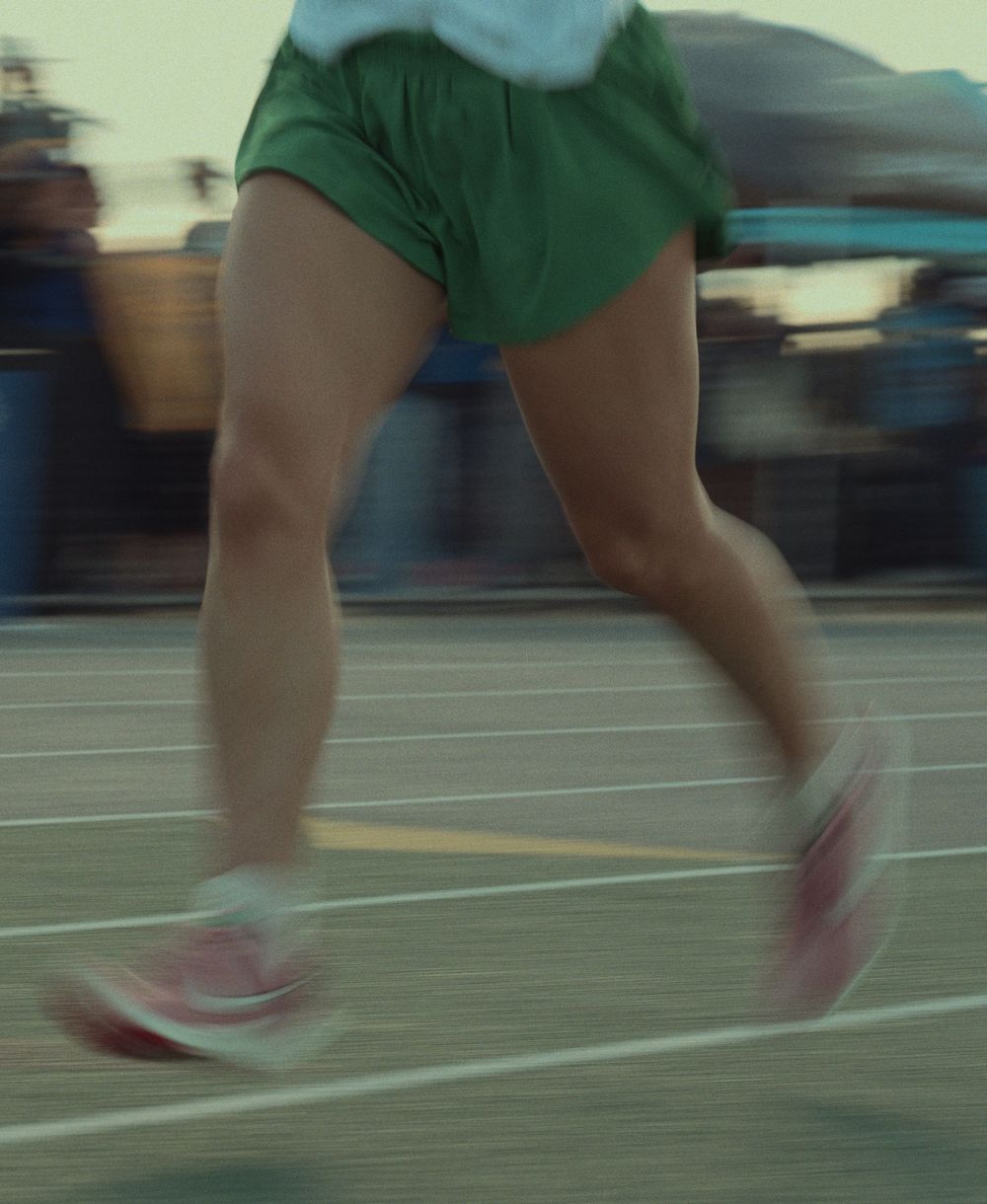 A sequence of motion shots showing lower legs and feet running on pavement in pink shoes and green shorts.