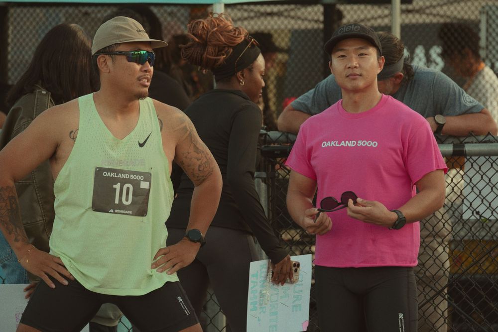 Two people wearing athletic attire standing next to each other, one in a mint green tank top and one in a pink t-shirt.