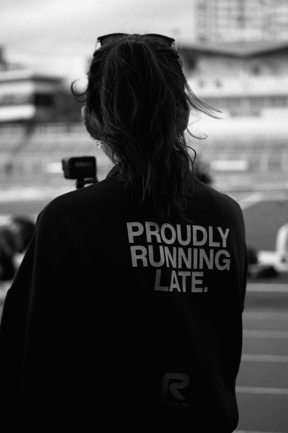 A series of back-facing black and white photos showing text on a jacket that reads 'PROUDLY RUNNING LATE'.