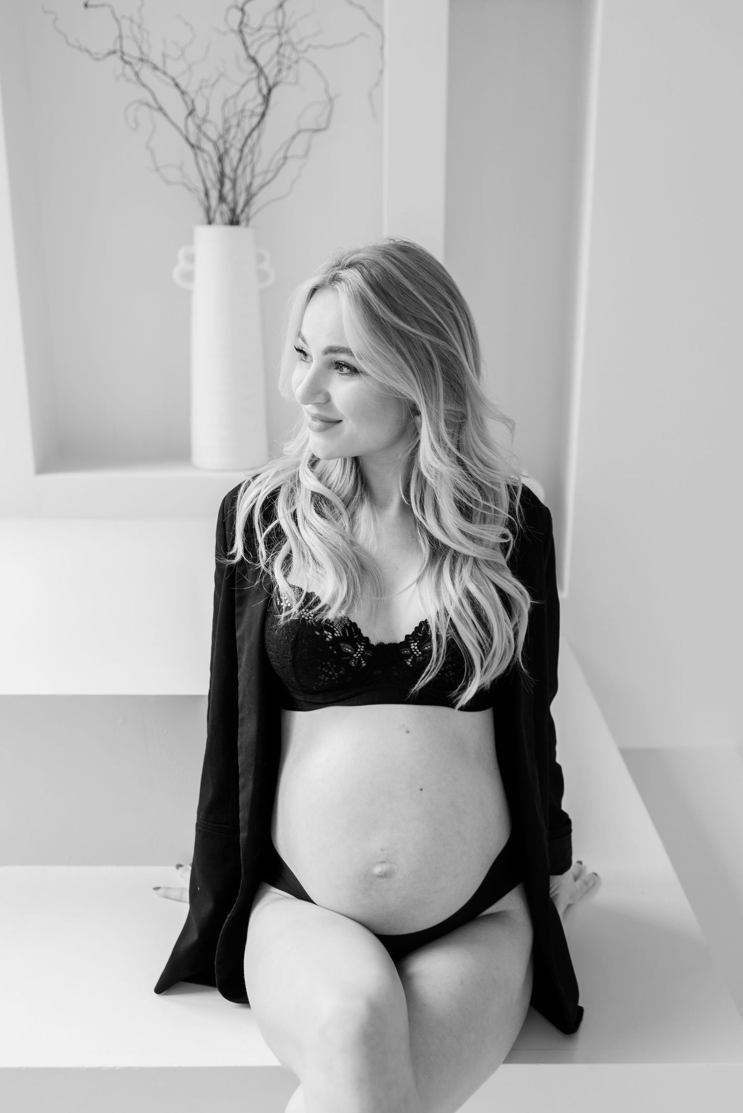 A series of black and white maternity photos showing a pregnant figure in a black top against a white backdrop.