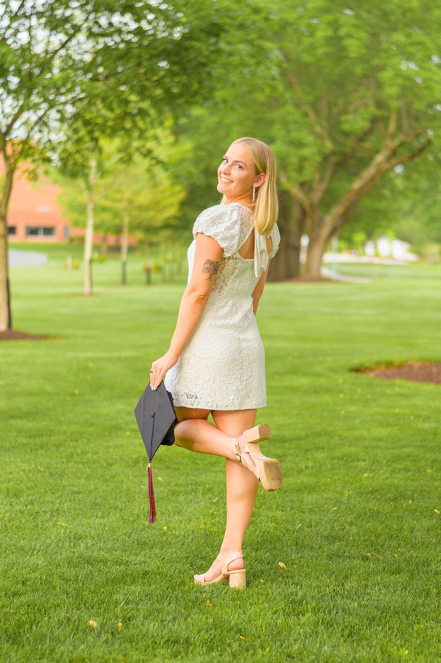 White lace dress flows gracefully against green grass in outdoor portrait setting.