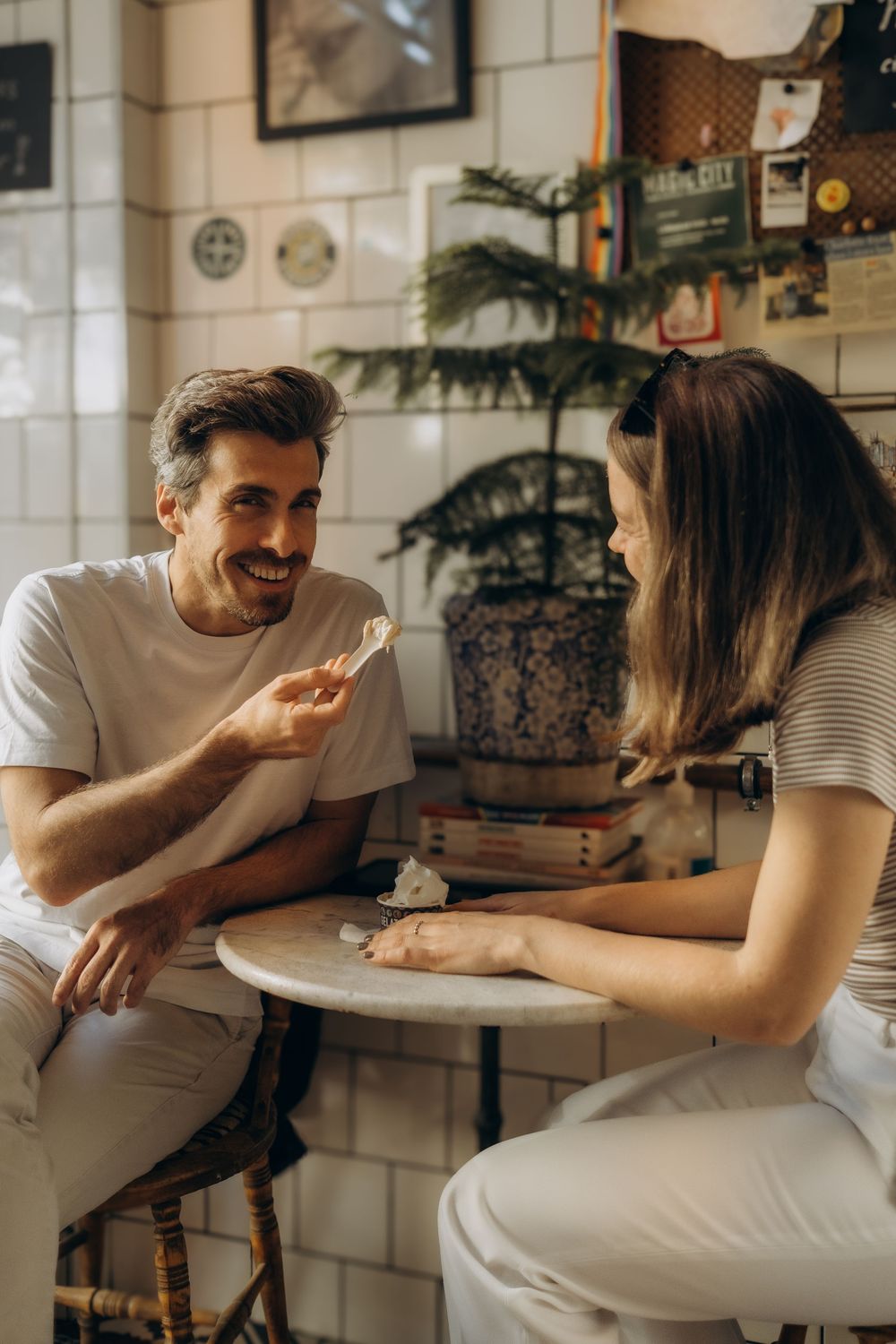 man feeding his girlfriend ice cream in ice cream shop during a vacation photo shoot for couples in Stockholm