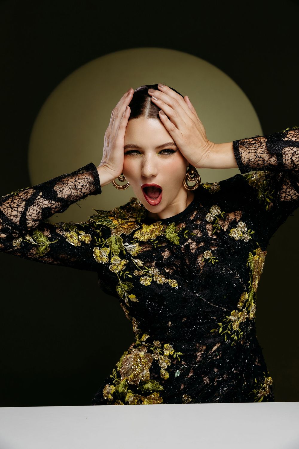 Dramatic fashion photo series showing model in black lace and gold sequins against dark background.