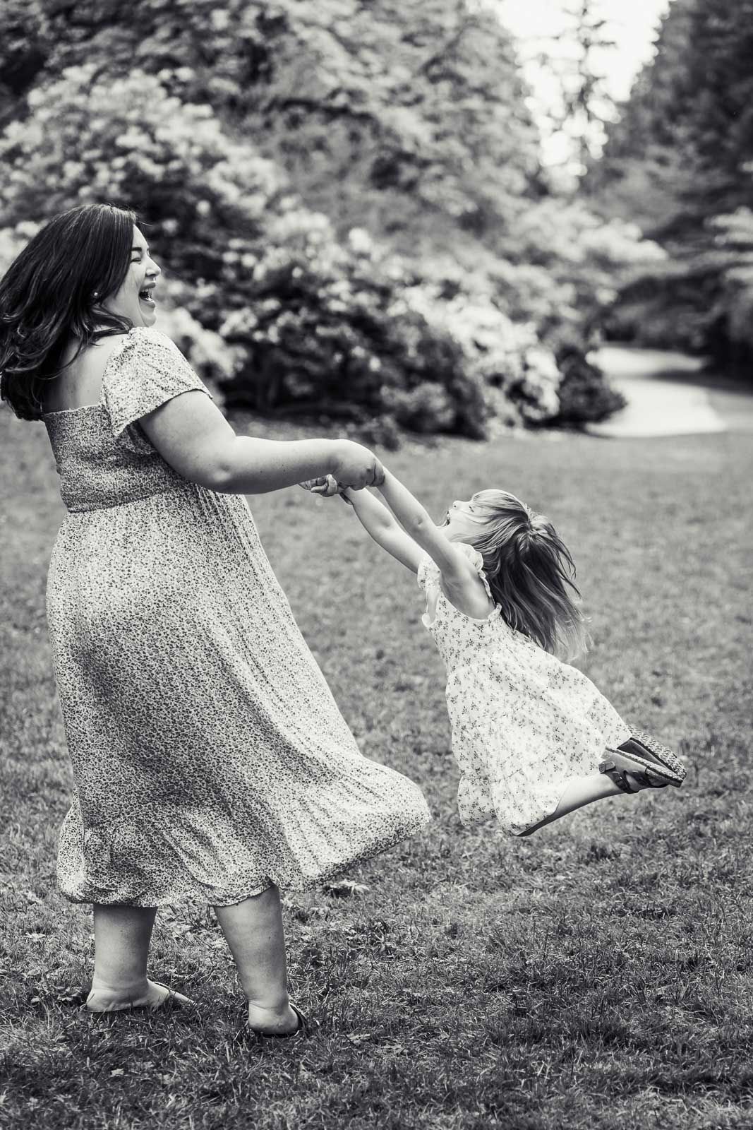 Mother swinging daughter in the air at a garden in Seattle.