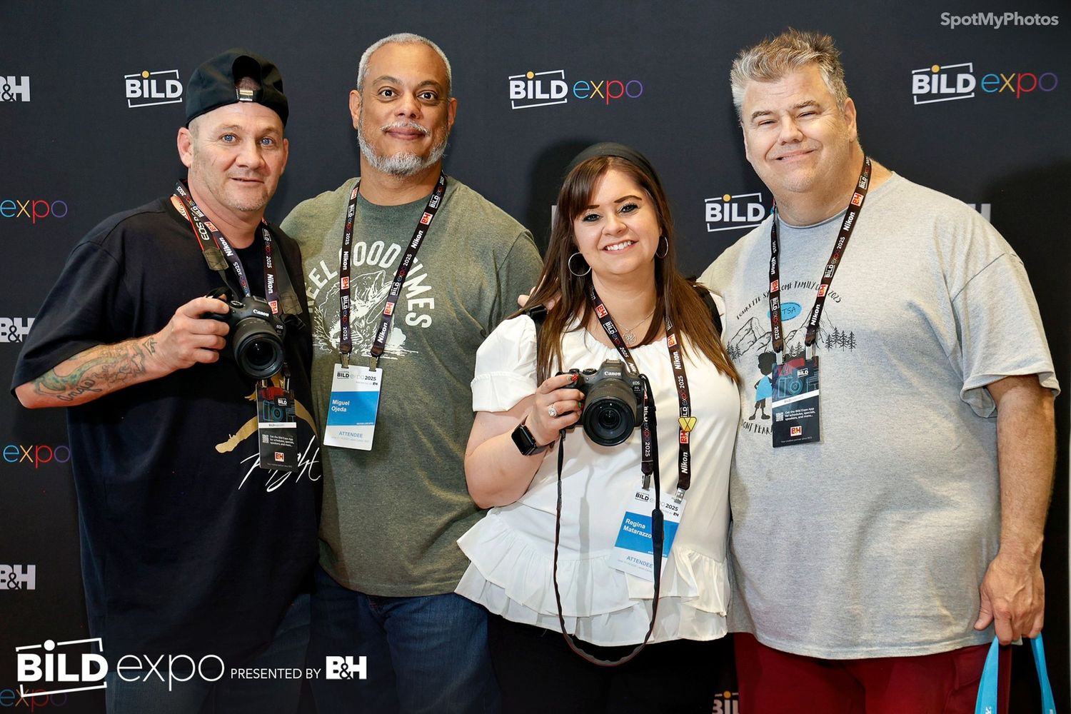 Group of people posing together at a conference event with name badges and smiling for photos.