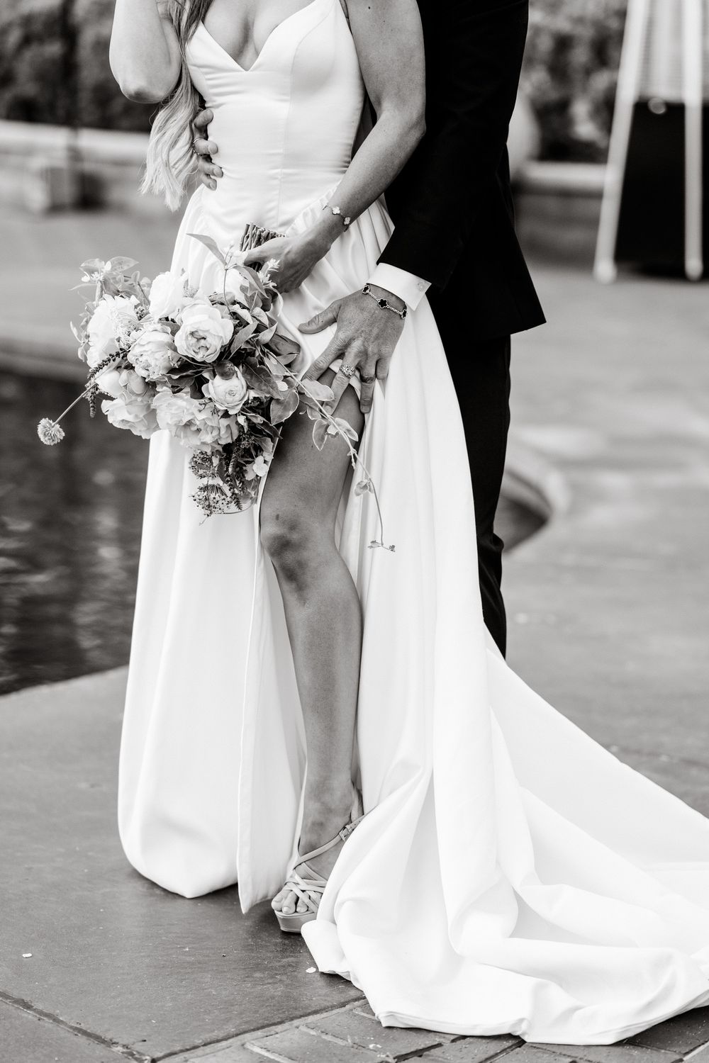 Black and white wedding photo showing bride holding floral bouquet with flowing white dress train.