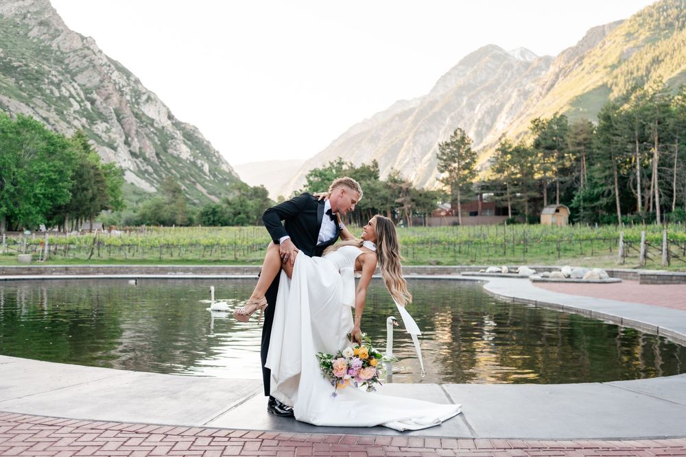 A couple shares a romantic moment near a serene mountain lake surrounded by evergreen trees and majestic peaks.