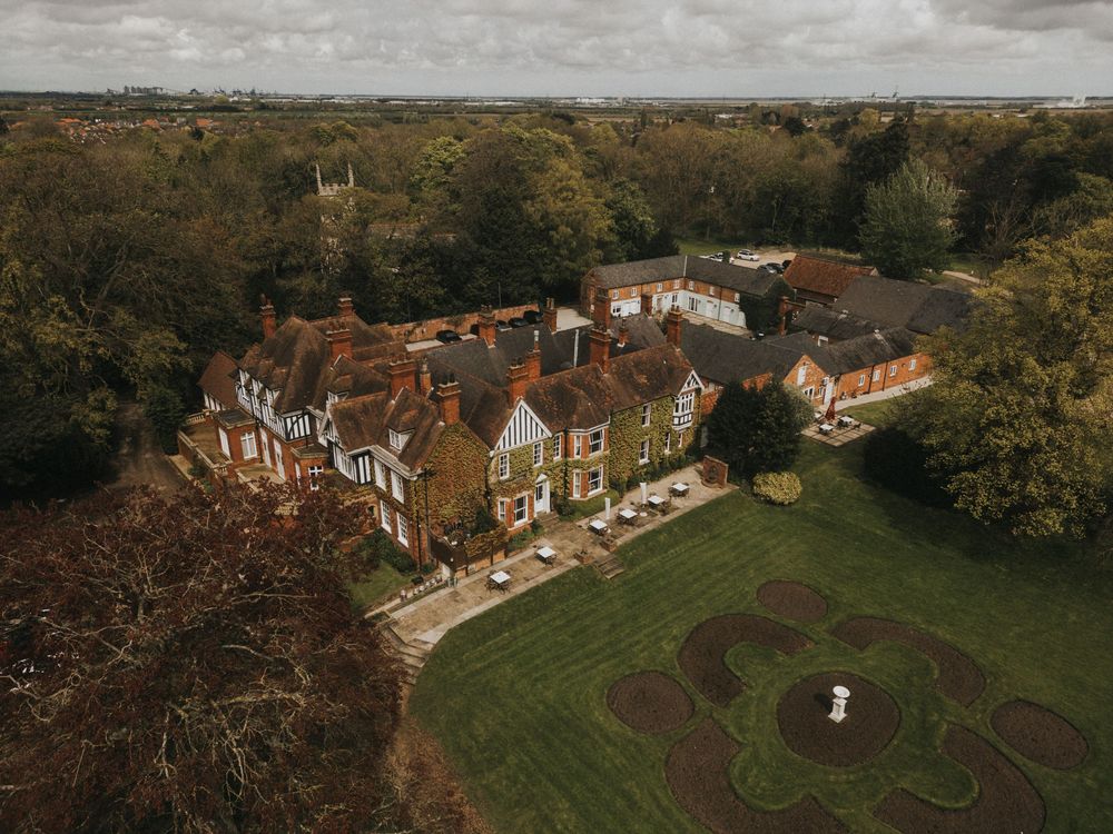 Aerial view of rolling green lawns and grand estates in an affluent residential neighborhood.