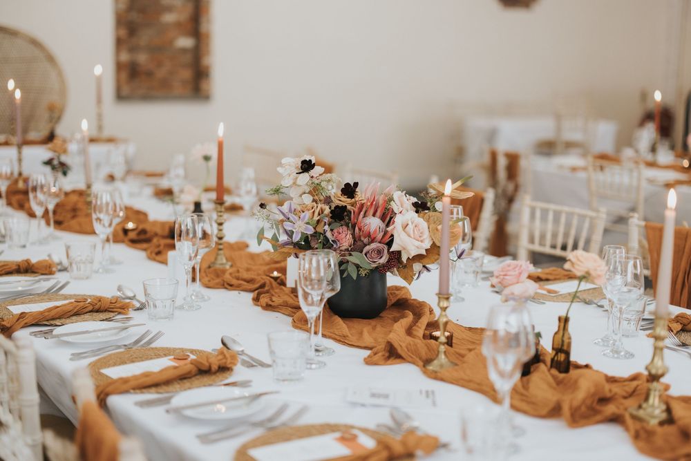 Elegant wedding reception table settings with white linens, gold accents, and soft floral centerpieces create a romantic atmosphere.