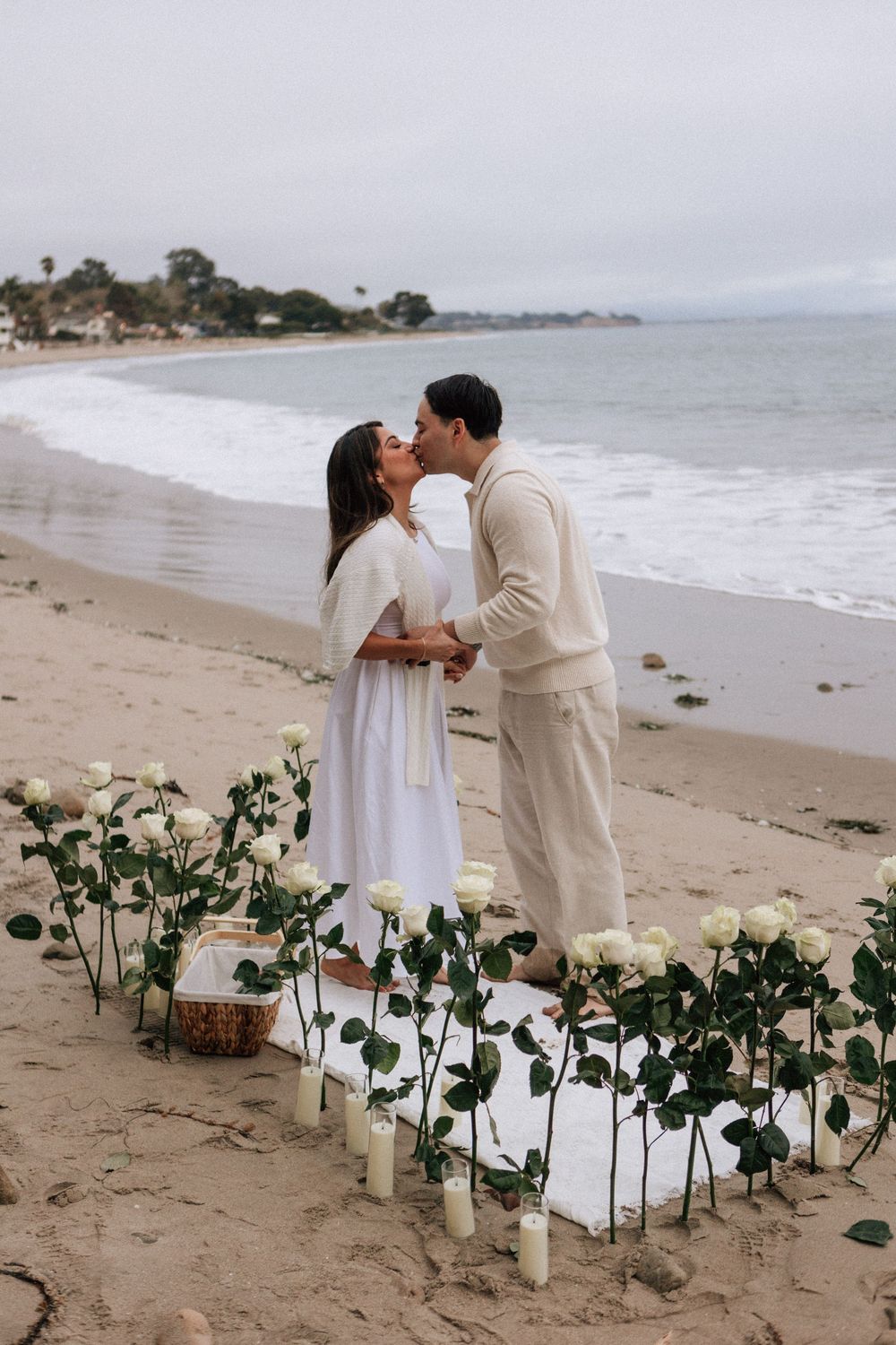 Couple walking barefoot along the shoreline after beach proposal.