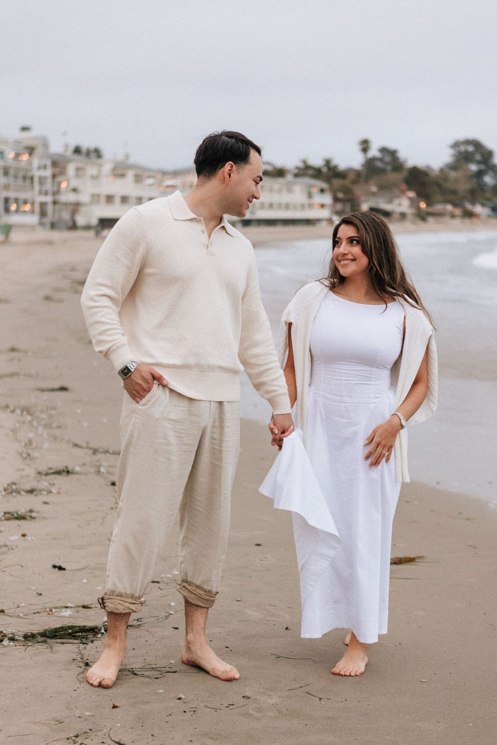 Detail of couple’s feet and rose petals scattered in the sand.