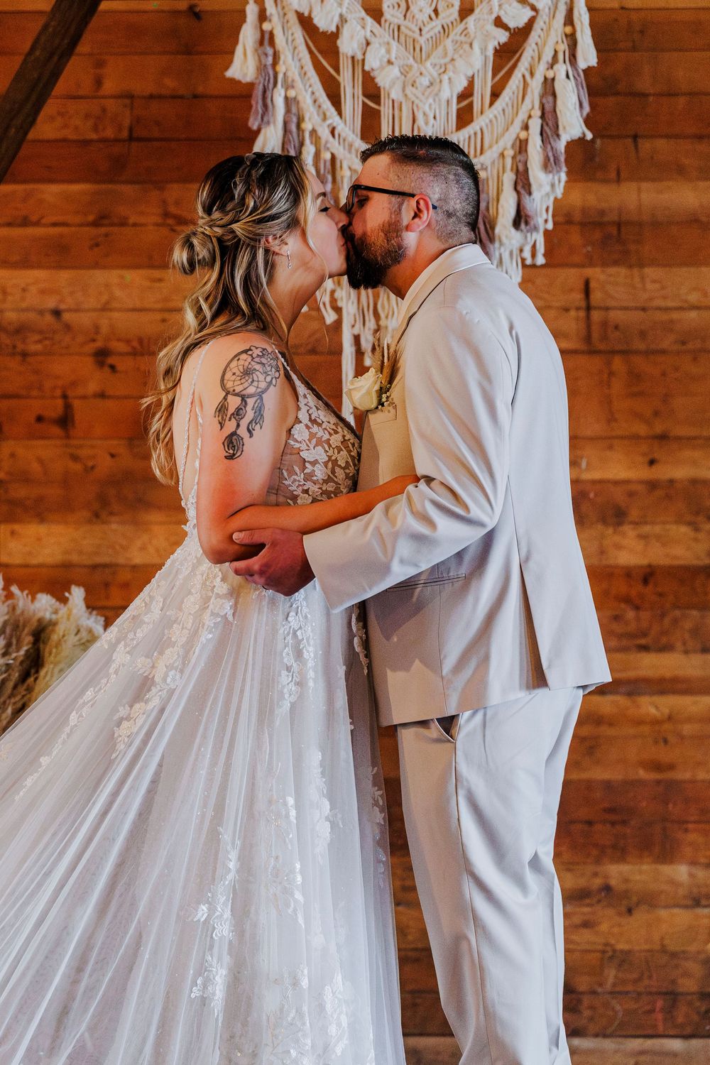 Romantic moment under macrame backdrop at rustic wooden venue.