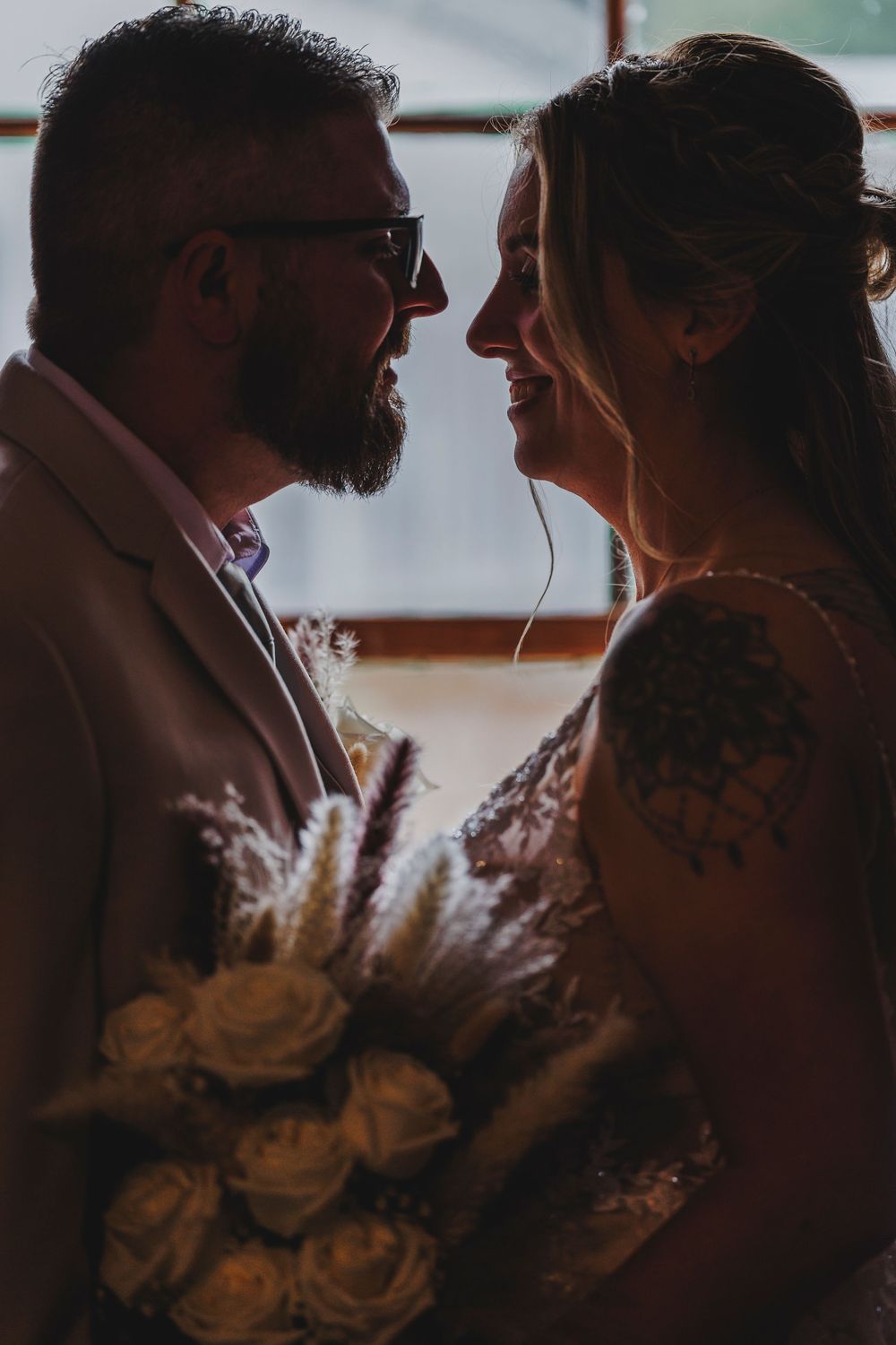 A romantic moment between a couple at their wedding with pampas grass and roses in the bouquet.