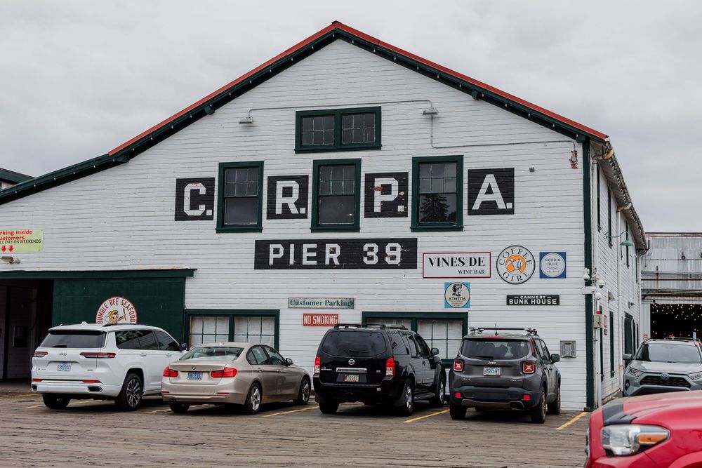 A white building with a red roof displaying signage for Pier 38 with parked cars in front.