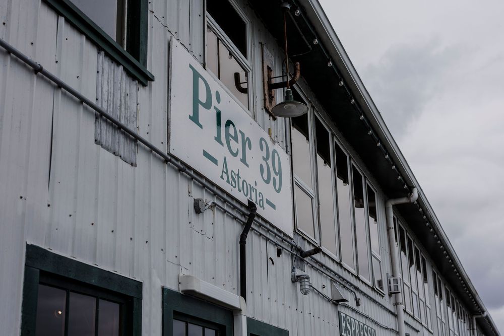 An old white industrial building with weathered siding and windows visible against a cloudy sky.