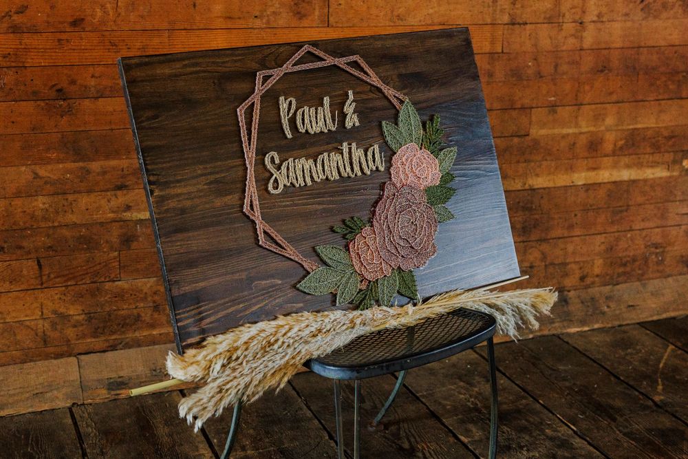 A rustic wooden wedding sign with floral details displaying Paul and Samantha's names.