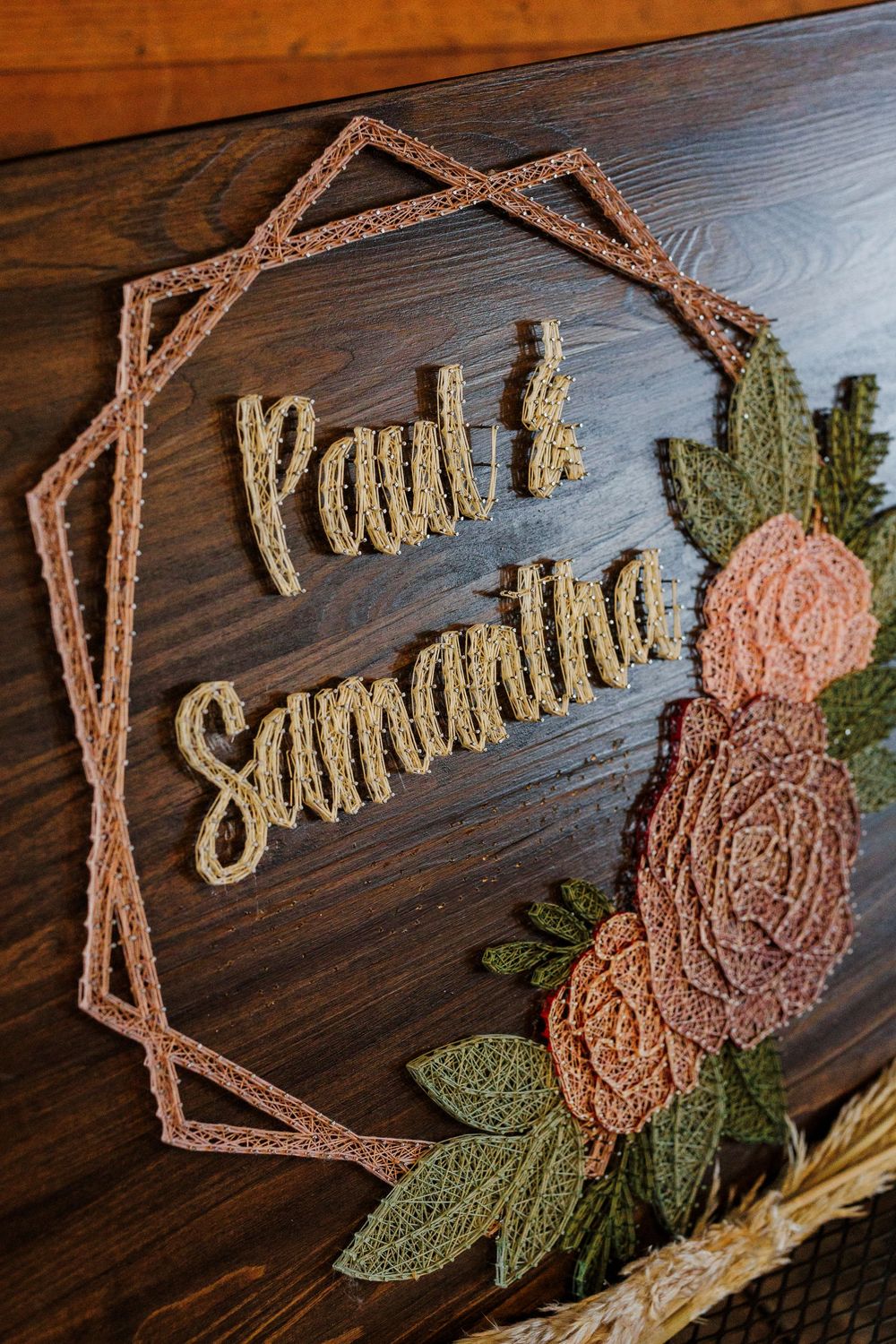 String art wall decor showing progress of creating rustic flower design with twine and nails on dark wooden board.