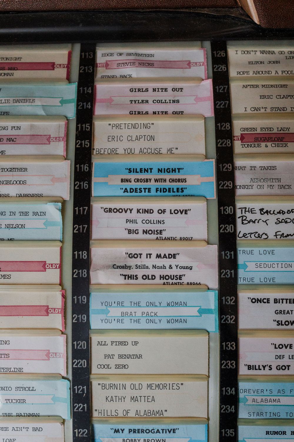 Vintage jukebox song selection cards showing classic rock titles in pastel colors.