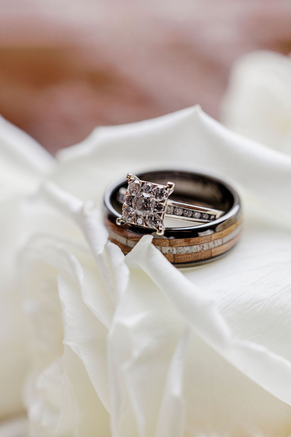 Diamond engagement ring and wedding band set photographed on white rose petals.