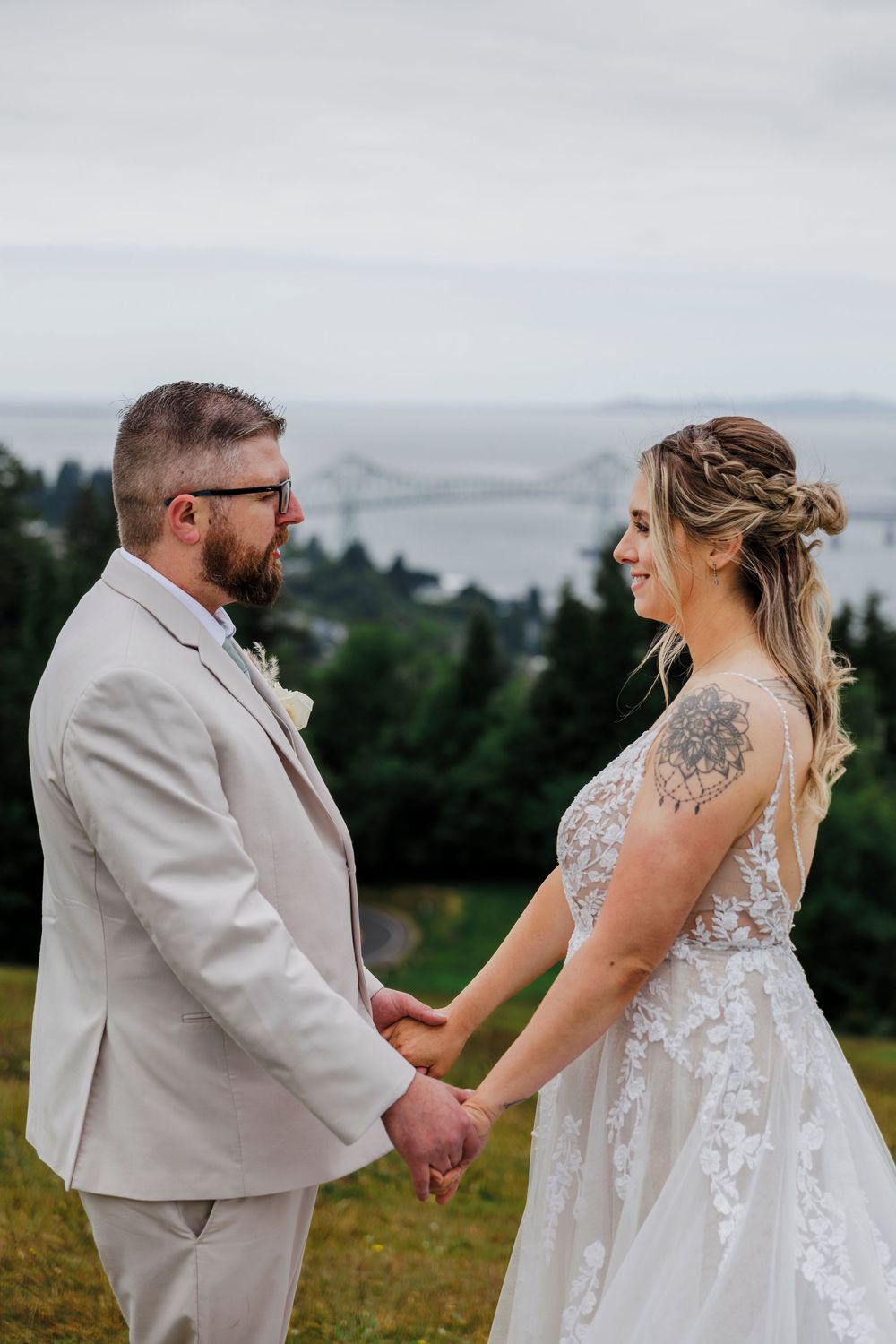 Wedding couple shares intimate moment on hilltop overlooking misty landscape.