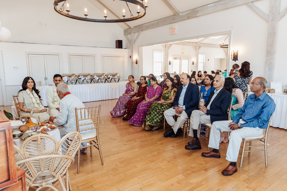 Wedding guests seated in rows at a bright indoor venue with wooden floors and white walls.