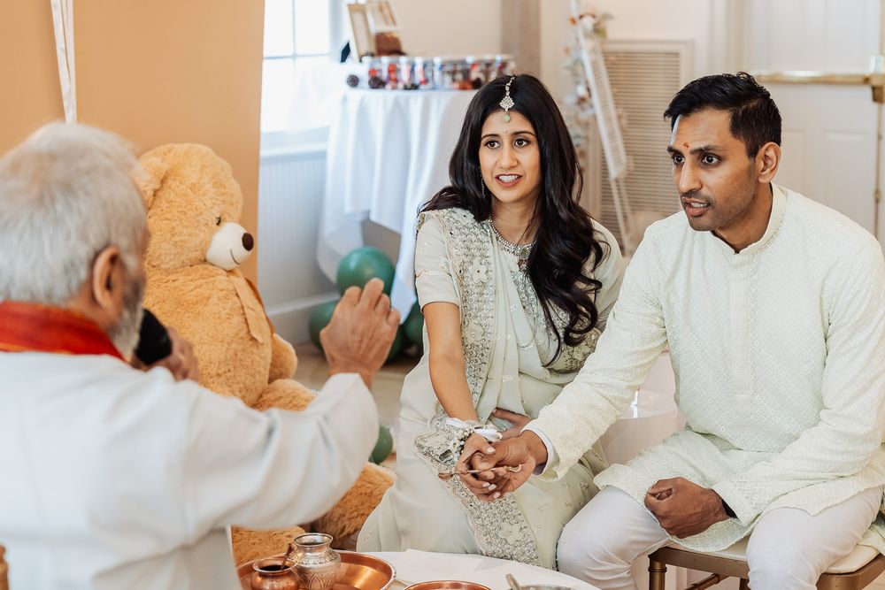 A traditional ceremony scene with participants in white attire and a large teddy bear in view.