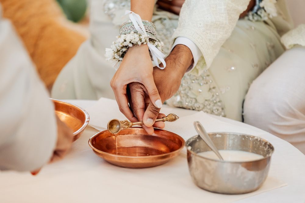 Close-up of hands participating in a traditional ceremony with metal bowls.