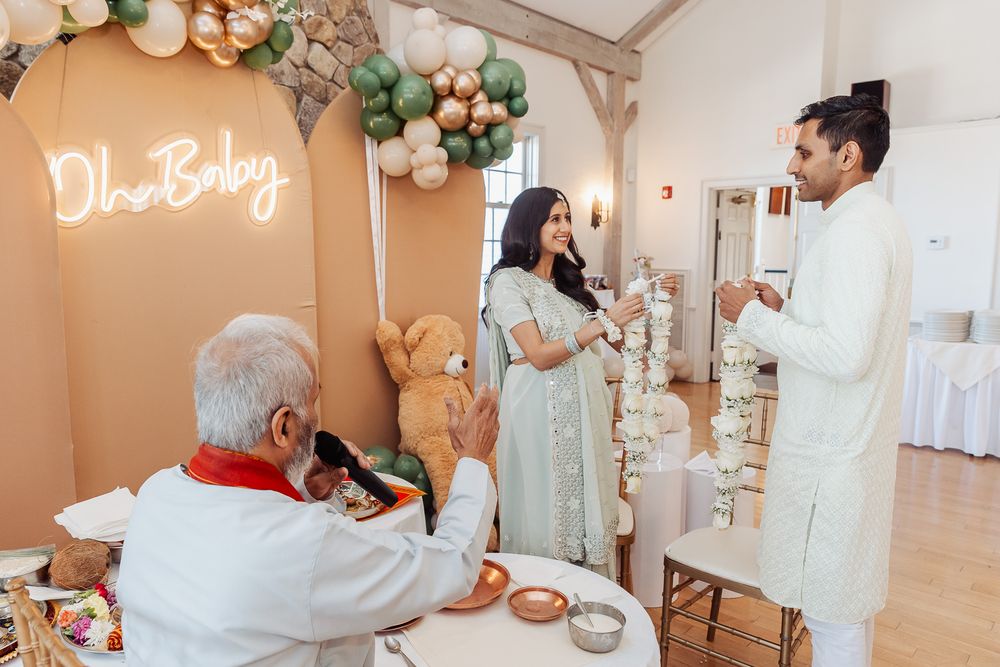 A decorated room with balloon arch, neon sign, and participants in traditional dress during a ceremony.