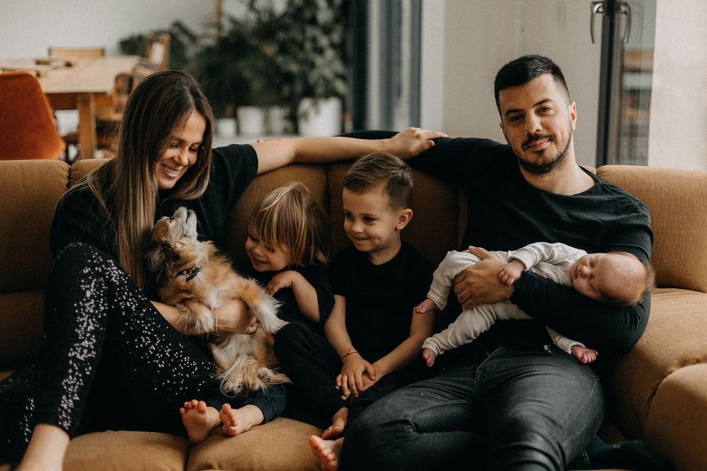 Family spending quality time together on a couch with their pets.