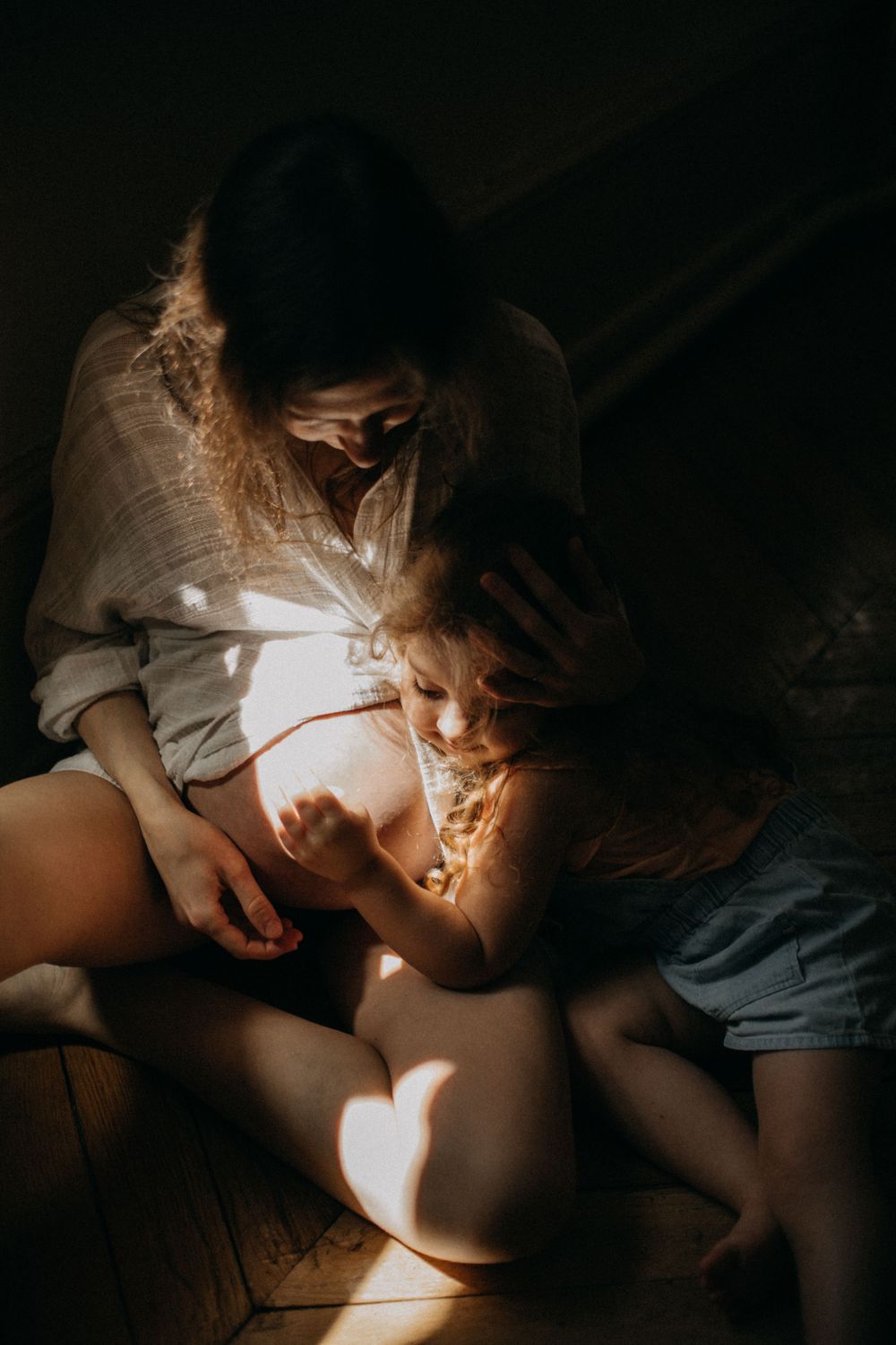 Intimate portrait of parent and child sharing tender moment in sunlit room.