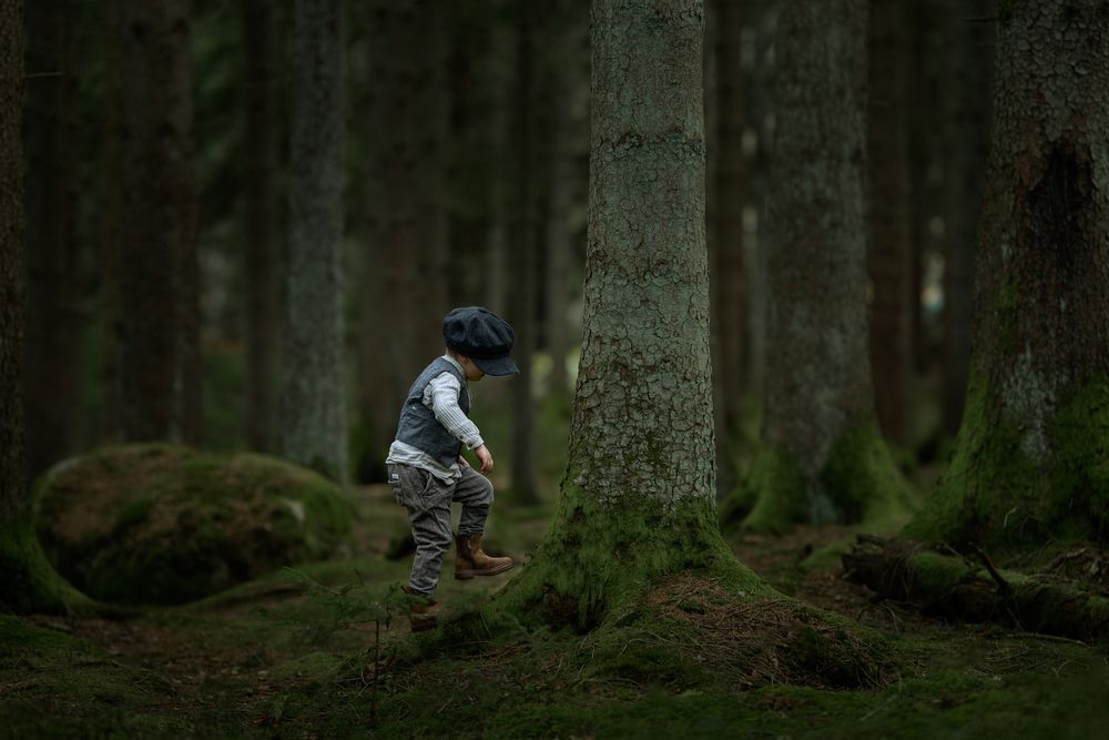 Pojke klädd i gammaldags kläder som upptäcker i skogen. Han försöker gå balansgång på en trädrot.