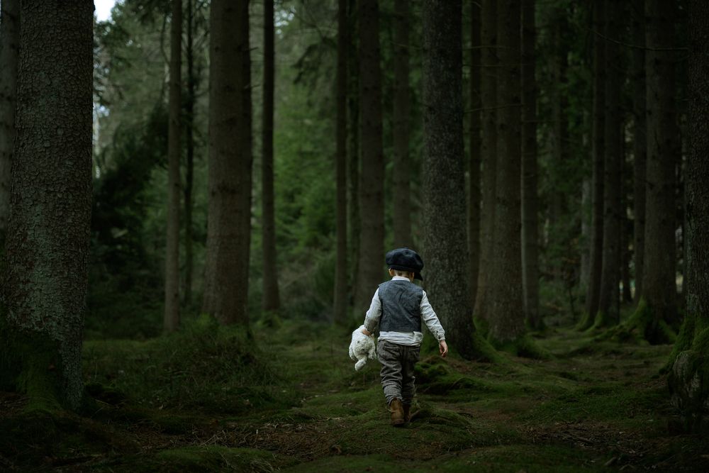 Pojke klädd i gammaldags kläder som upptäcker i skogen.