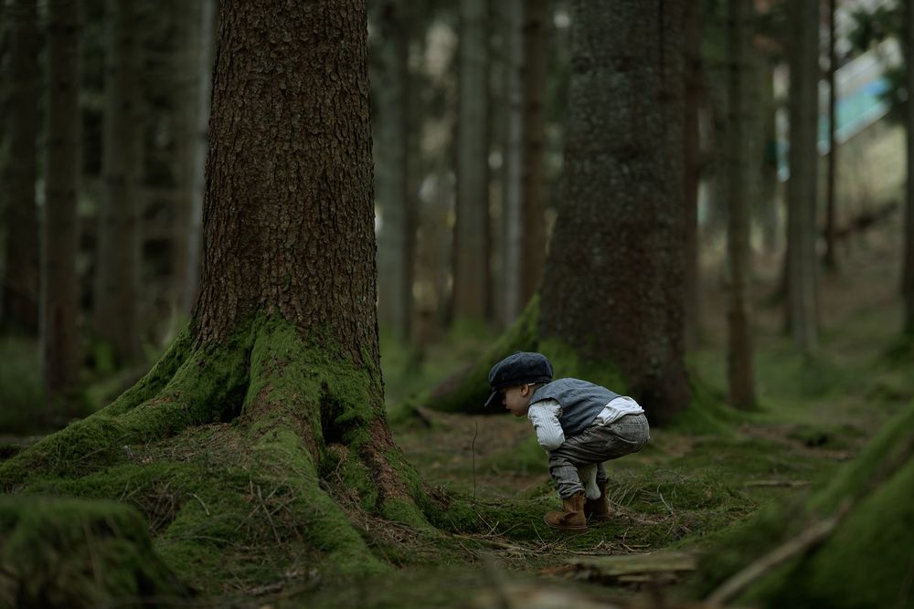 Pojke klädd i gammaldags kläder som upptäcker i skogen.