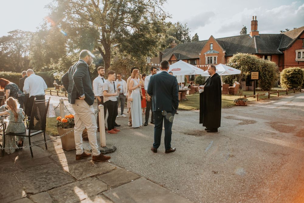Small gathering of people standing outside a traditional brick building on a sunny autumn afternoon.