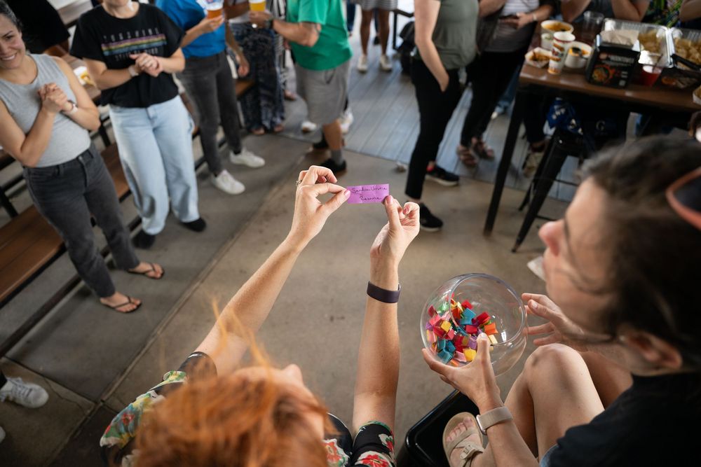 People watching attentively during a soap bubble demonstration in a casual indoor setting with a glass bowl on the table.