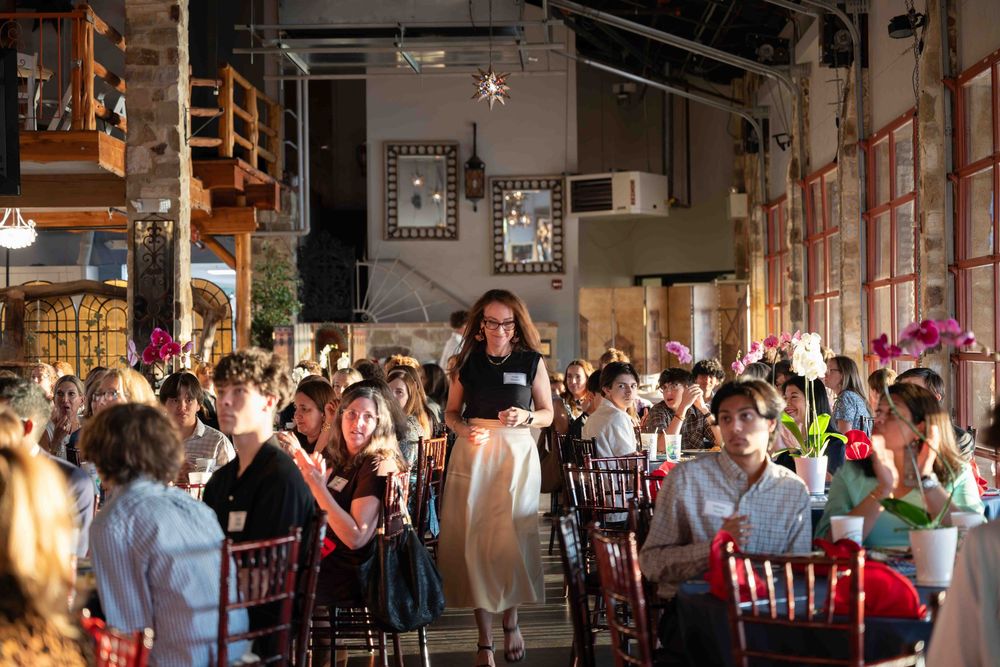 Restaurant servers tend to diners in an industrial-style venue with exposed brick walls and high ceilings during a busy service.