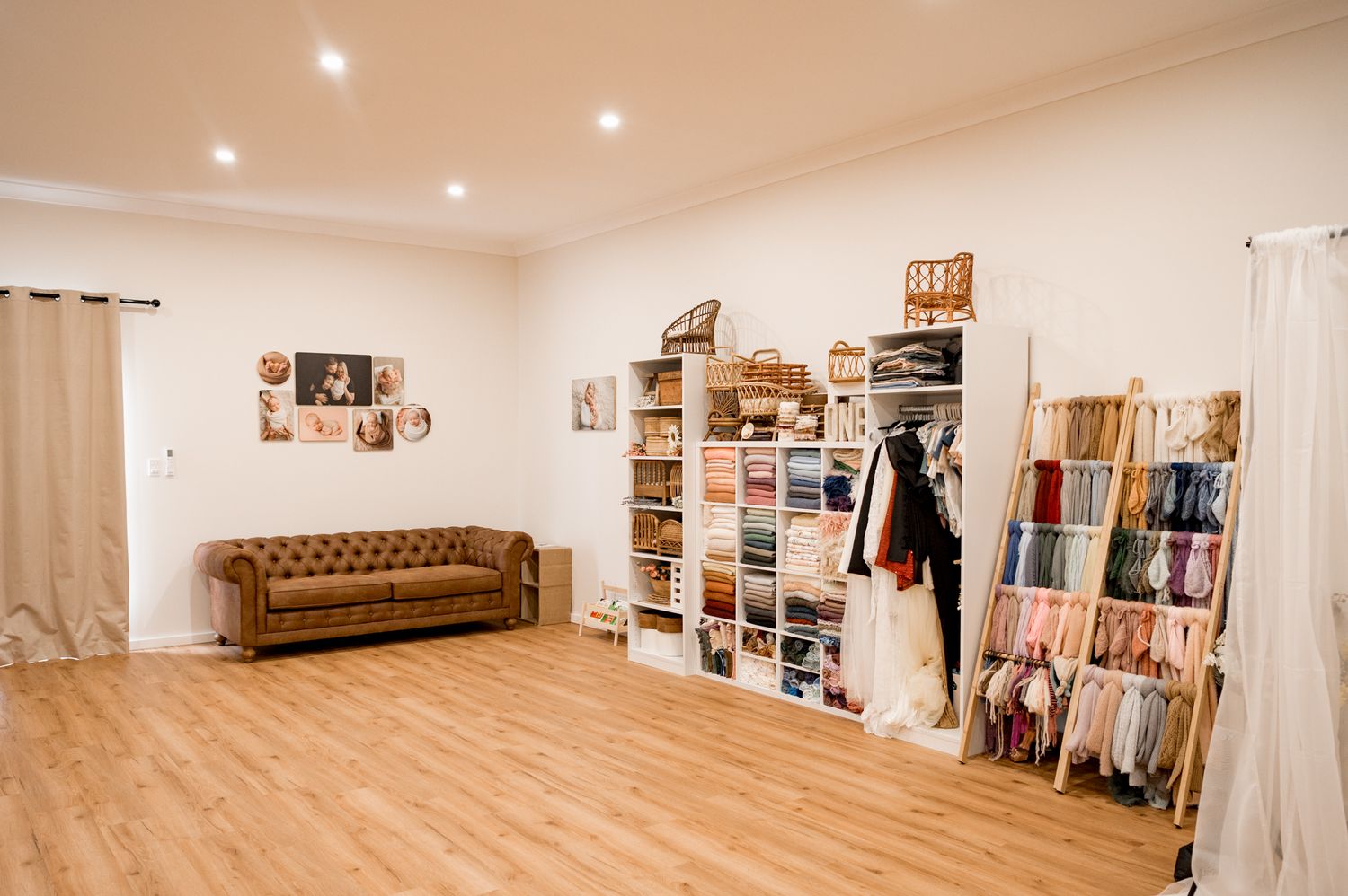 Modern studio space with brown leather couch, white walls, recessed lighting, and organized shelving displaying retail items.