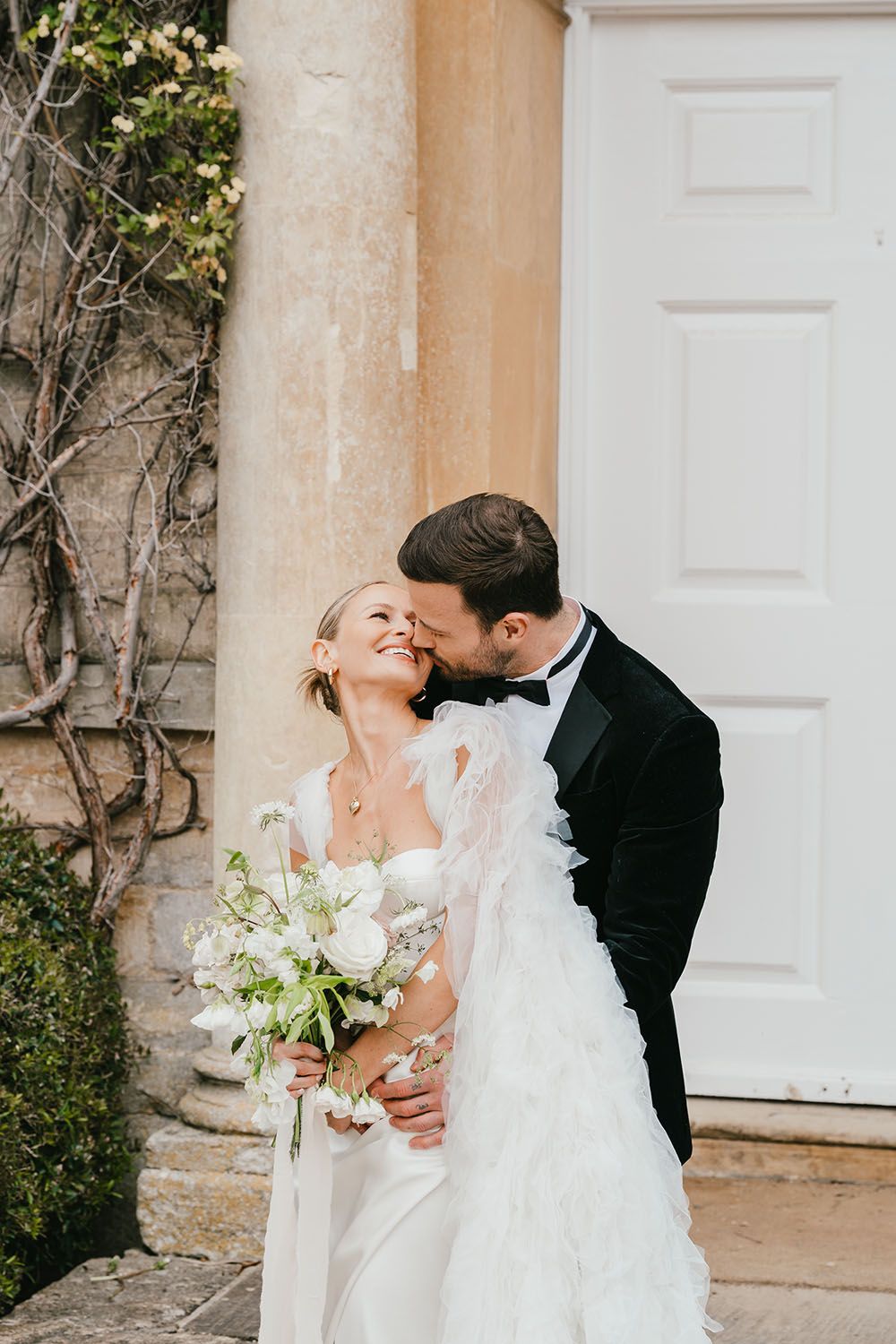 Stylish bride and groom sitting in front of a grand door