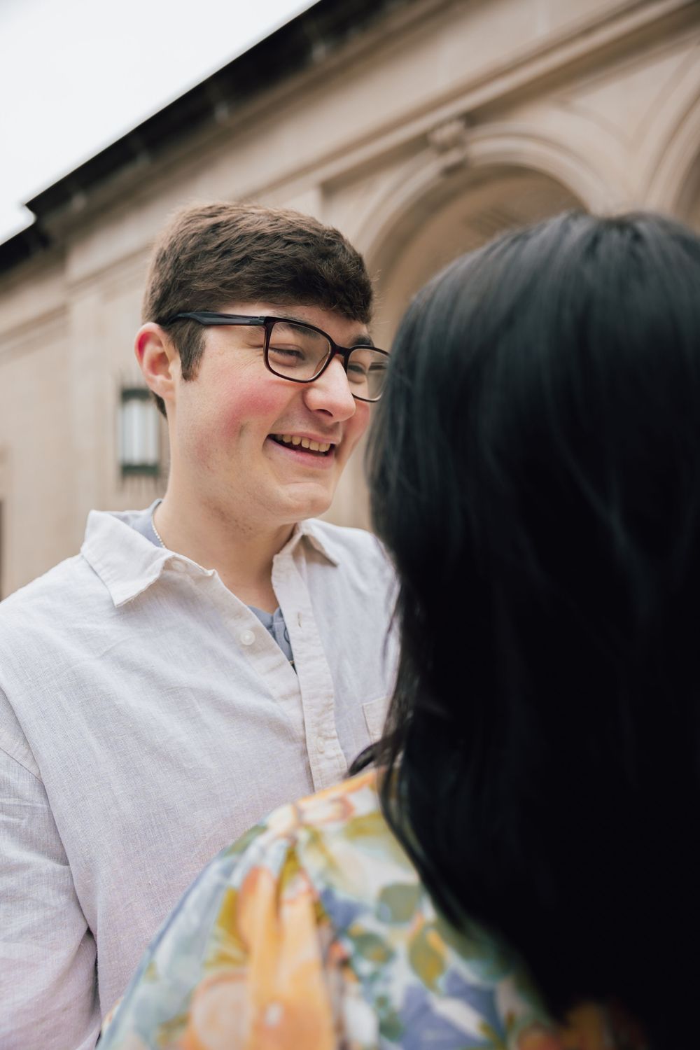 Two people in conversation share a cheerful moment outside a building.