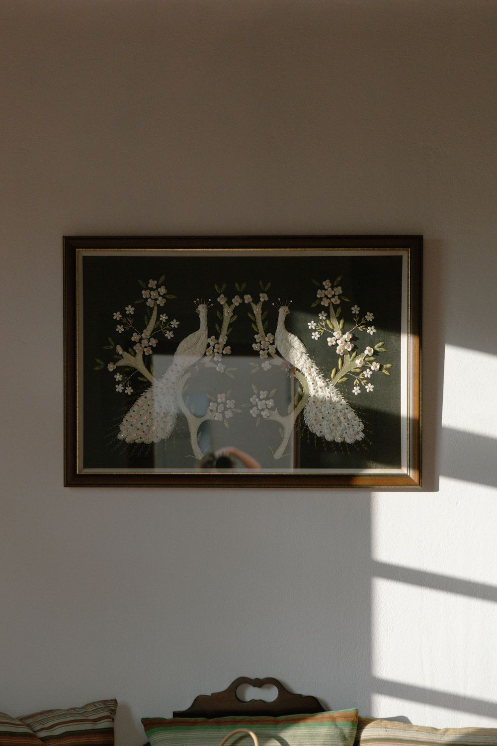 Framed artwork of white peacocks and flowering branches in morning light.