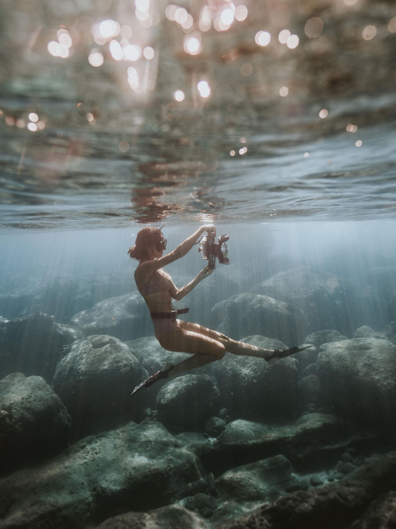 woman taking underwater photo on Maui wearing weight belt, snorkeling mask and flippers