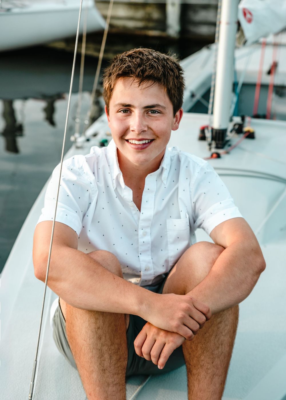 Casual summer portrait of a young person in white shirt sitting on a boat.