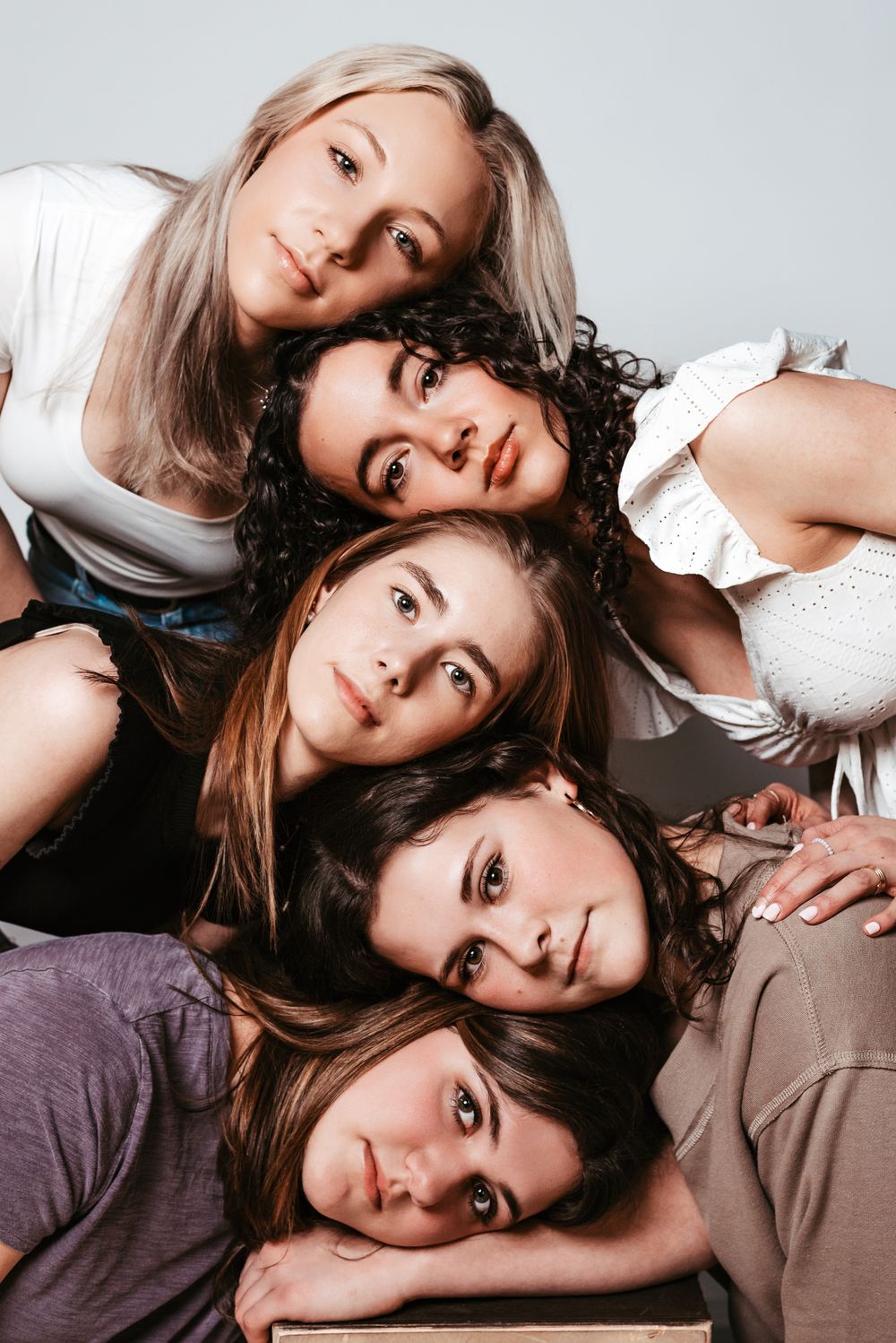 Creative portrait of five people laying in circular formation with heads together.