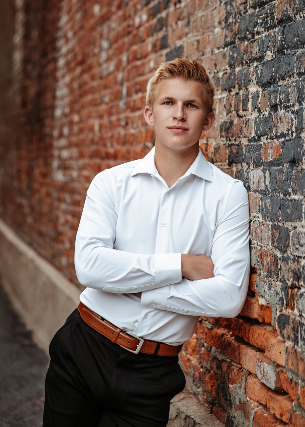 Professional portrait against brick wall wearing crisp white dress shirt.